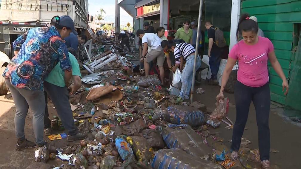 Moradores mexem na lama para encontrar alimentos perdidos por supermercado Foto ReproduoRBS TV
