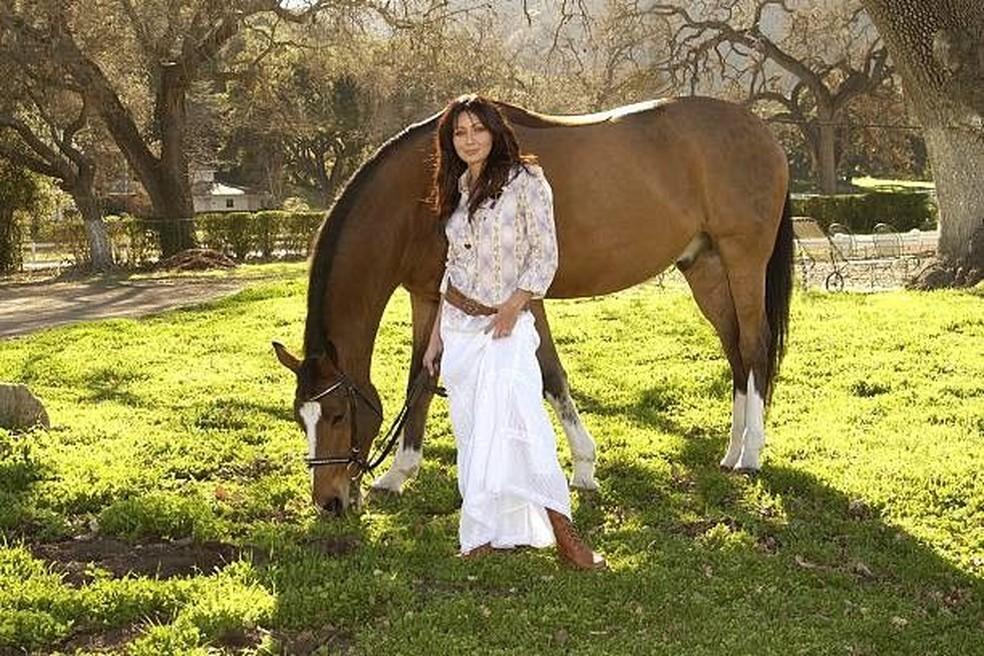 Image: https://mulherinteressante.com/wp-content/uploads/2024/07/postiimg-66944d30285ea3836.jpg Shannen com um dos cavalos na sua propriedade no Tennessee alguns anos atrs Foto Reproduo